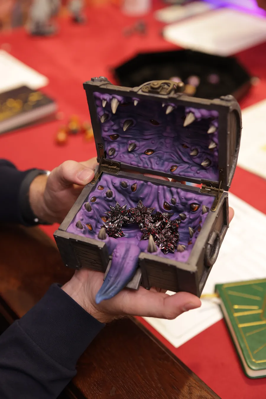 A player holds the open Mimic Dice Box at the table
