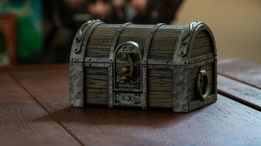 The closed Mimic Dice Box on a wooden table, disguised as a treasure chest